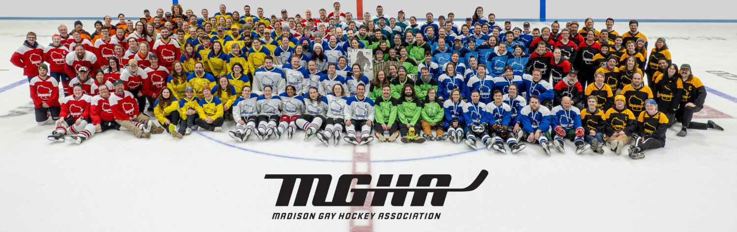 Over a hundred people sit in a spread of rainbow hockey jerseys on an ice rink, smiling at the camera.